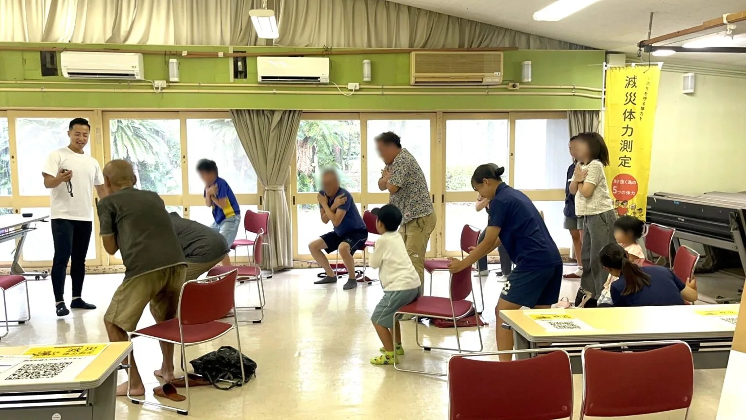 会場で参加者が椅子からの立ち上がりテストに取り組む様子(顔は加工処理済み)